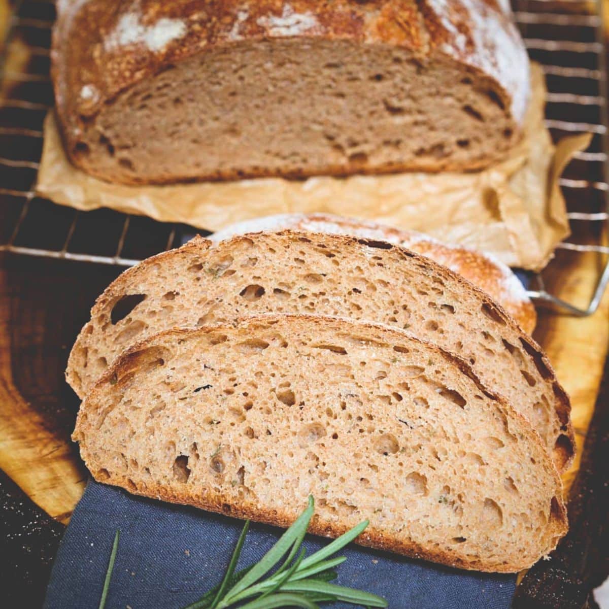 Angled view of sliced rosemary spelt sourdough sitting on a linen napkin. Hostess At Heart