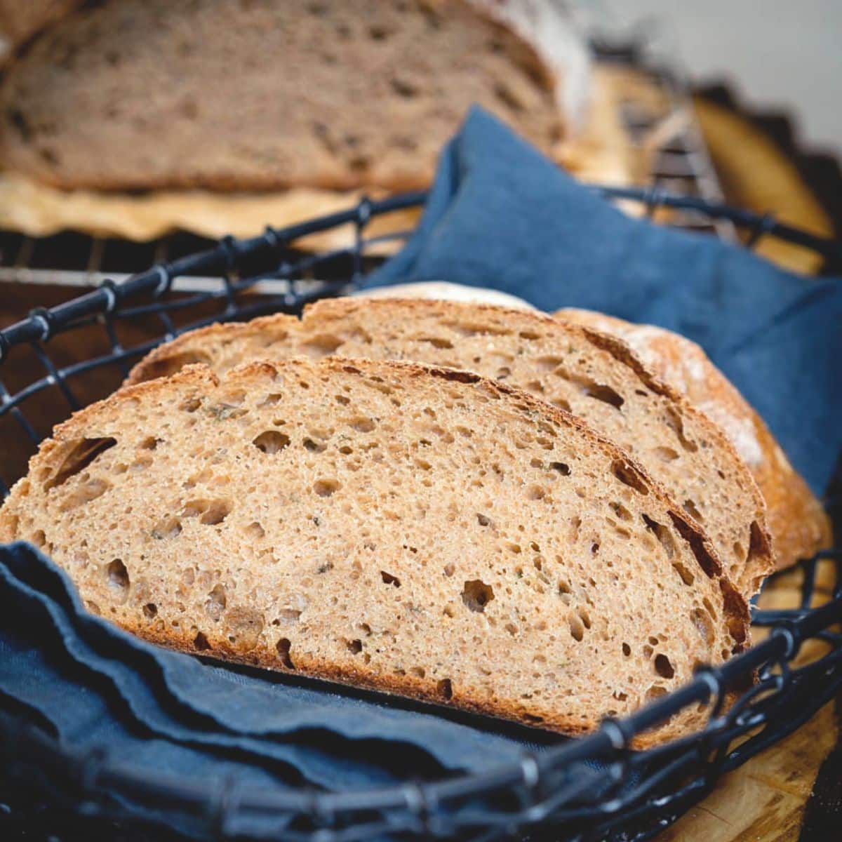 A basket lined with a linen napkin holding two slices of spelt sourdough bread fresh from the oven. Hostess At Heart