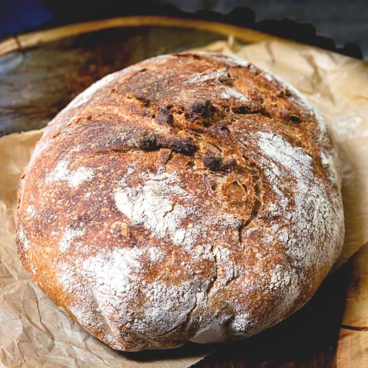 Angled view of a loaf of rustic spelt sourdough bread baked to a golden brown. Hostess At Heart