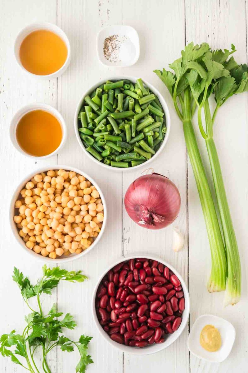 Ingredients for three bean salad including chickpeas, kidney beans, green beans, celery, and red onion, maple syrup, Dijon mustard and apple cider vinegar. Hostess At Heart