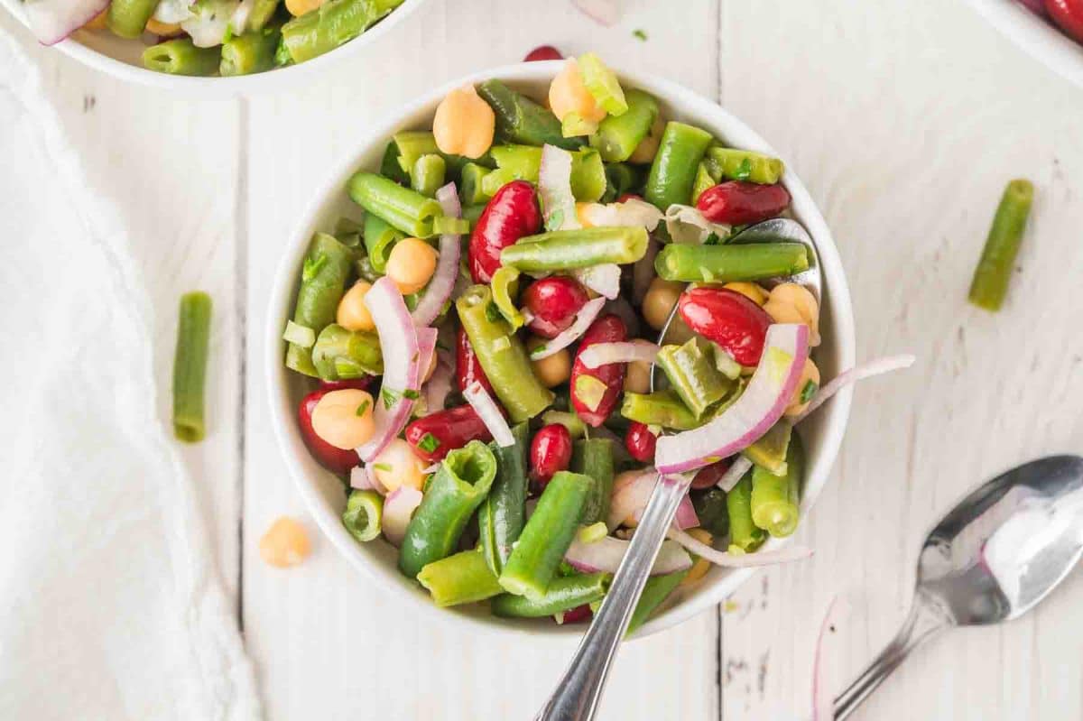 Easy three bean salad recipe with chickpeas, kidney beans, and green beans in a white bowl. Hostess At Heart