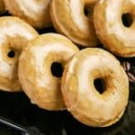 A black tray filled with glazed coffee doughnuts ready to be served. Hostess At Heart