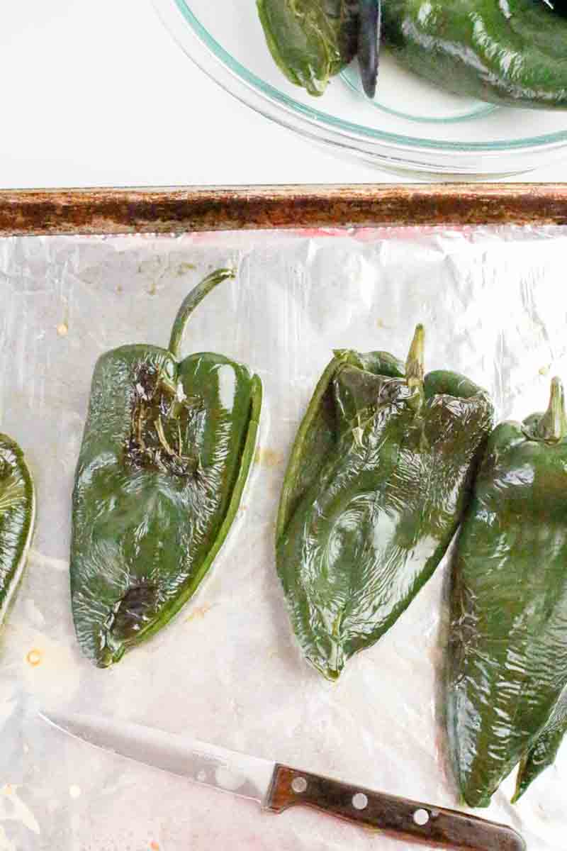 Roasted poblano peppers on a baking sheet with blistered charred skins - queso cheese dip prop. Hostess At Heart