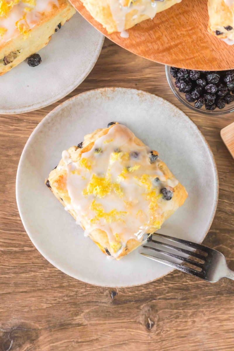 Top down view of a homemade blueberry biscuit on a serving plate next to a fork. Hostess At Heart