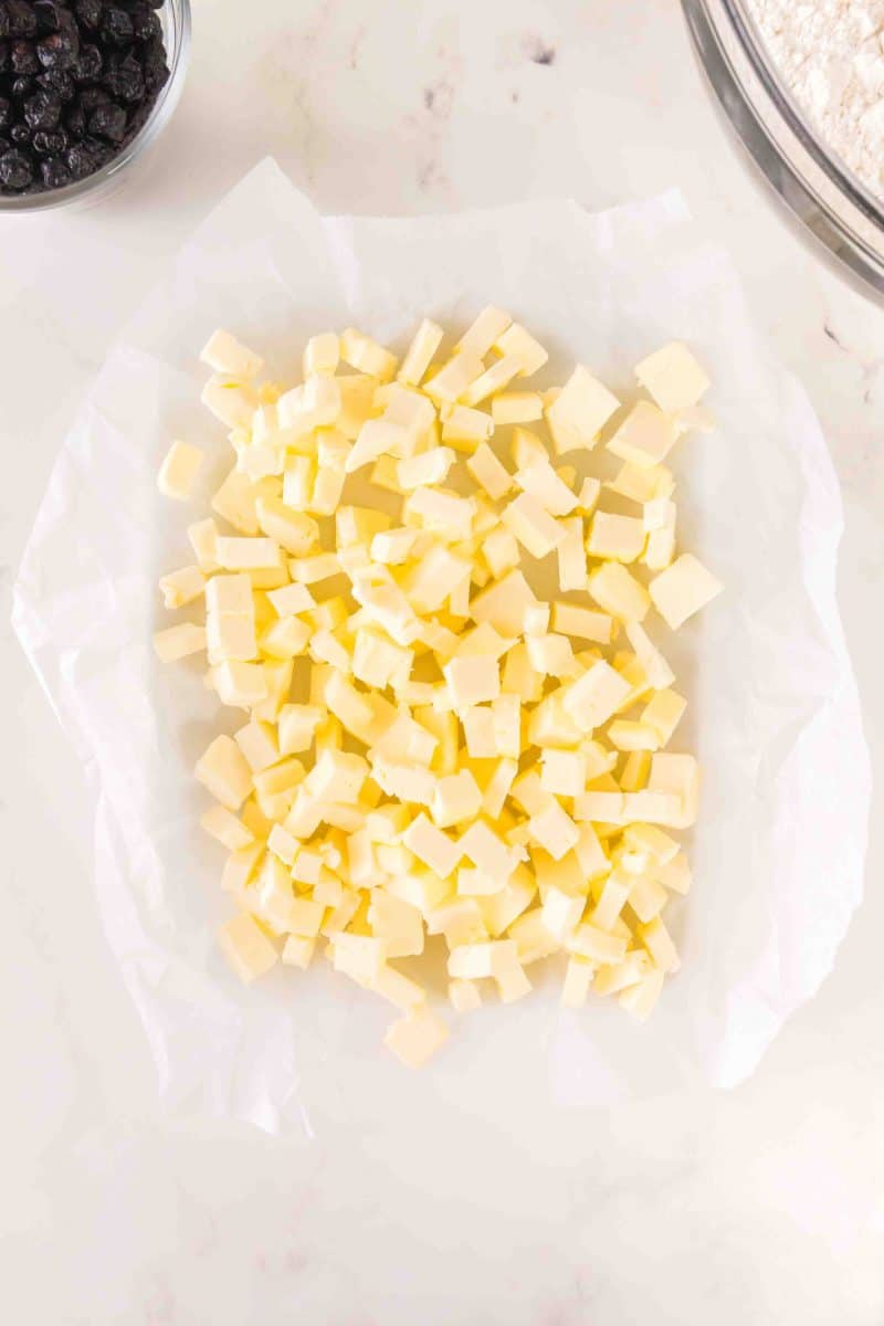 Top down view of cold butter properly cut into cubes on parchment paper. Hostess At Heart