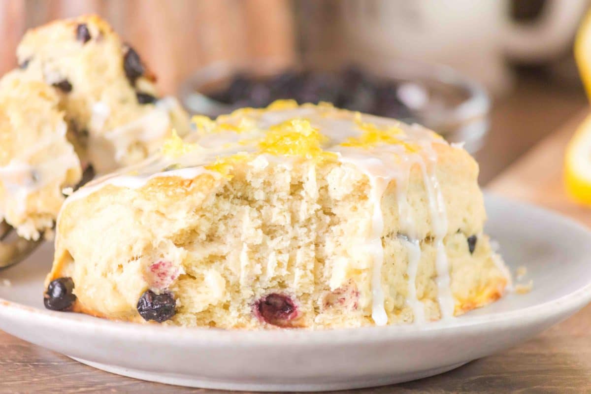 Blueberry biscuit with a forkful missing showing a fluffy buttery interior with blueberries. Hostess At Heart