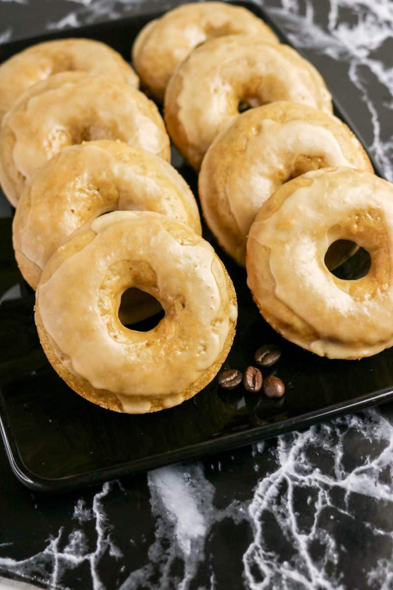 Front view of glazed coffee doughnuts arranged in a line on a serving tray. Hostess At Heart