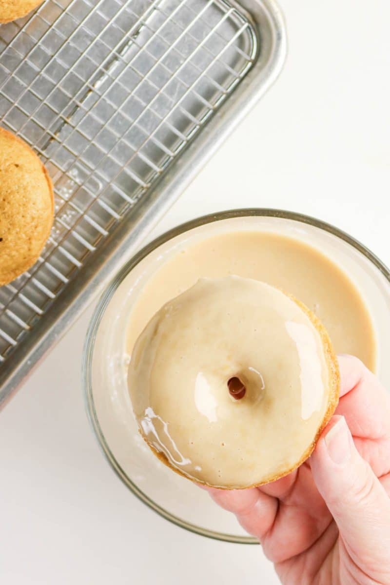 Dipping a baked coffee donut into shiny coffee glaze. Hostess At Heart