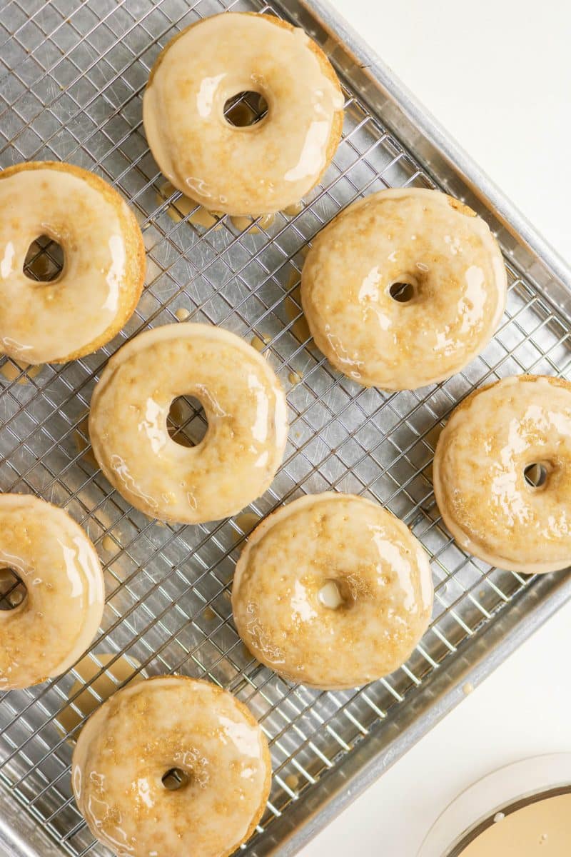 Top down view of freshly glazed coffee donuts drying on a rack topped baking pan. Hostess At Heart