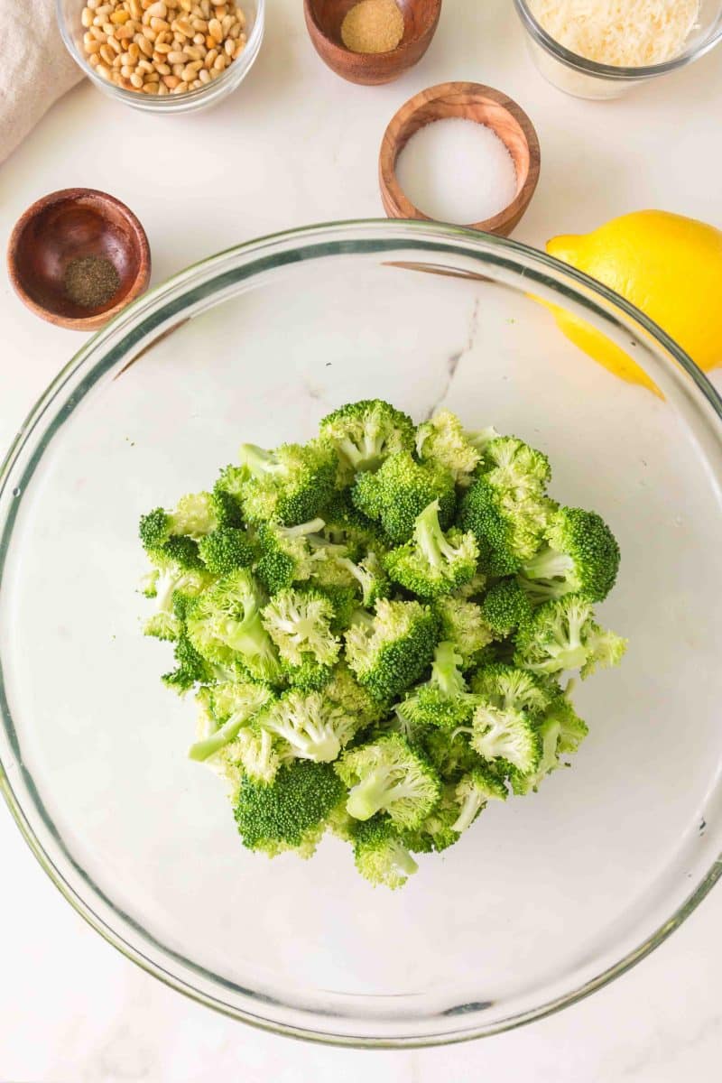Broccoli florets in a large bowl ready to be tossed with olive oil and lemon juice. Hostess At Heart