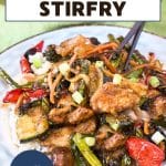 An image for Pinterest of a plate filled with colorful stirfried veggies and crispy brown pieces of chicken in an Asian sauce over rice. Hostess At Heart