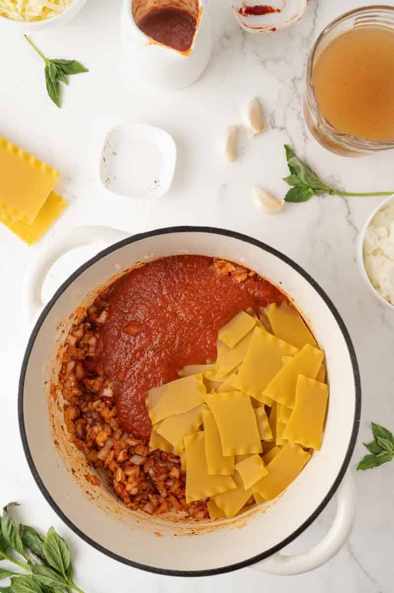 Broken lasagna noodles added into a simmering tomato vegetable broth. Hostess At Heart