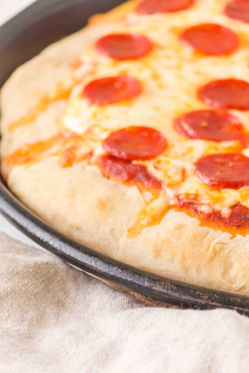 3/4 Tableview of a baked pizza make with No Knead dough topped with pepperoni and cheese. Hostess At Heart