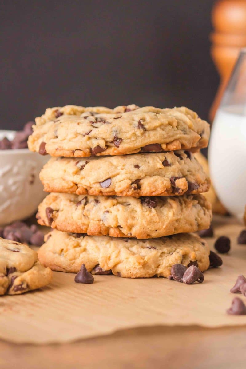 Thick crumble chocolate chip cookies stacked on a wooden surface. Hostess At Heart