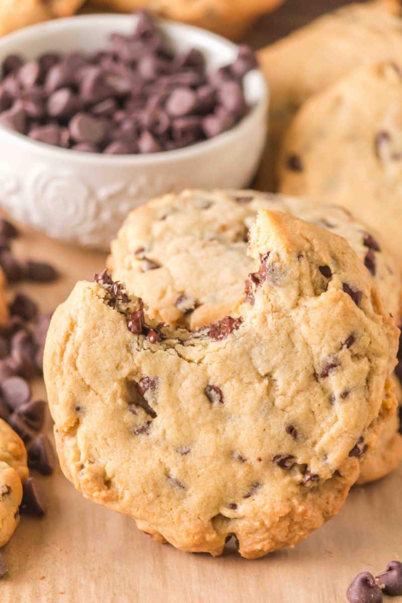 A soft golden brown crumble chocolate chip cookie leaning against another cookie. Hostess At Heart