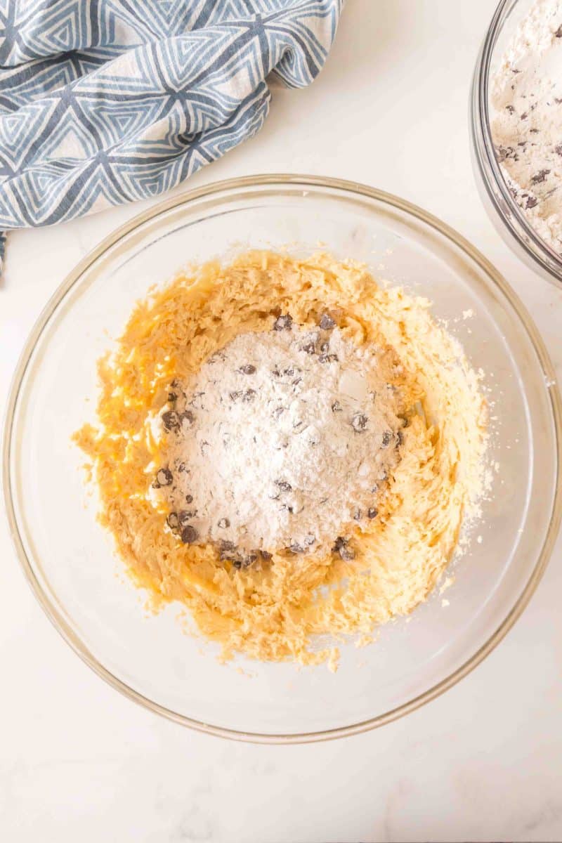 Dry ingredients mixed with chocolate chips added to crumble cookie batter in a mixing bowl. Hostess At Heart