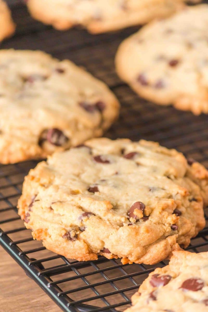 Angled view of thick golden brown baked crumble chocolate chip cookies cooling on a wire rack. Hostess At Heart