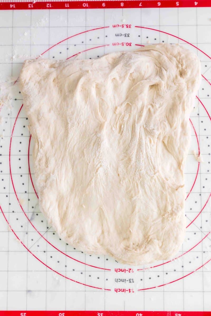 No knead dough stretched on a pastry mat for shaping before the second rise. Hostess At Heart