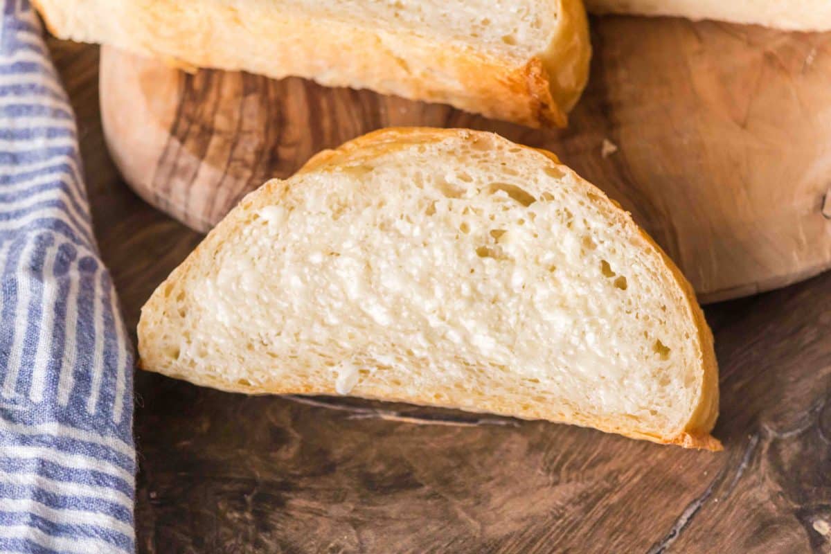 A slice of French Bread from a baguette baked on a baking sheet showing a slightly flatter bottom. Hostess At Heart