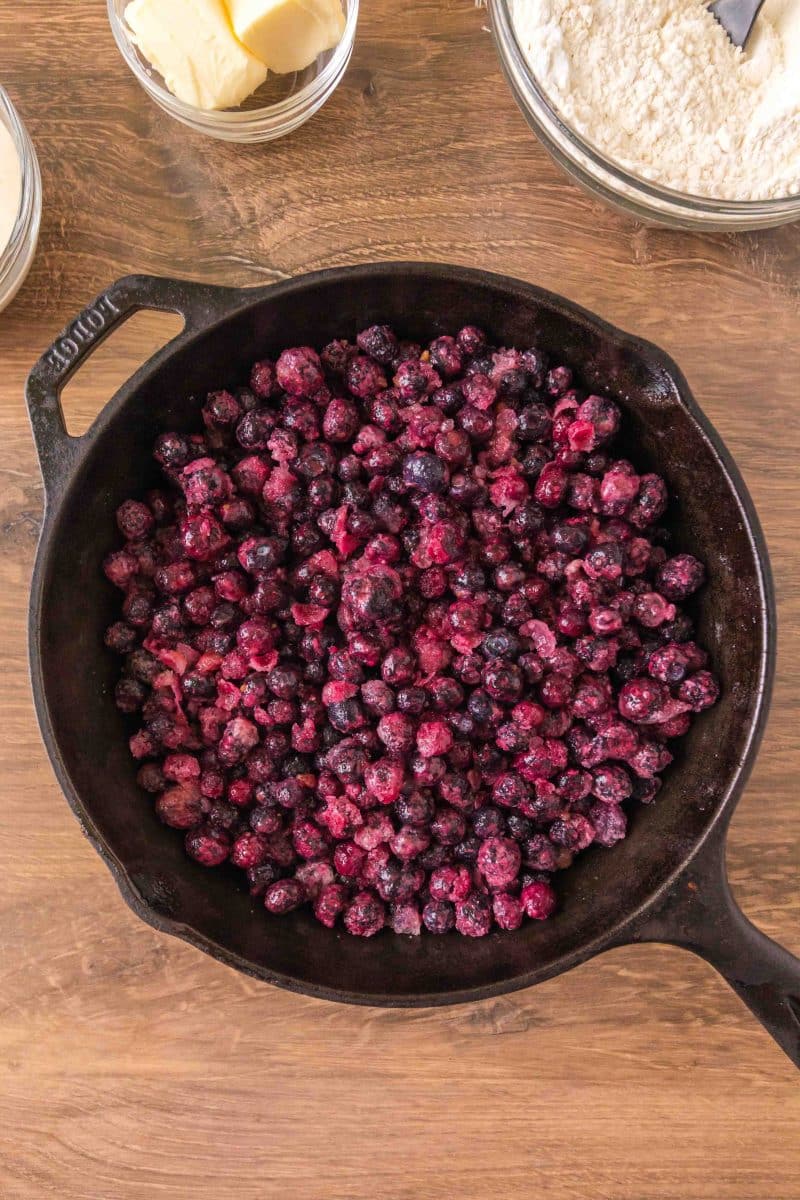 A cast iron skillet filled with an unbaked sourdough discard blueberry cobbler filling. Hostess At Heart