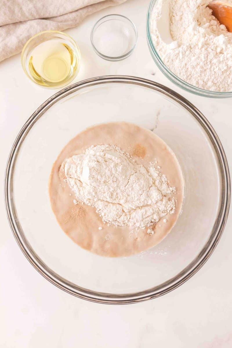 Flour added to a mixing bowl containing yeast activated with sugar and warm water. Hostess At Heart