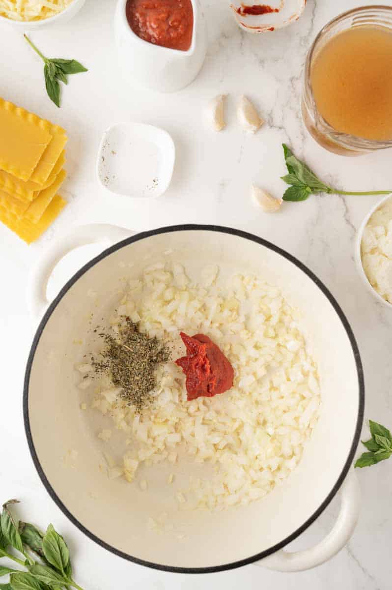 Diced onion, minced garlic, tomato paste and Italian seasoning stirred together in a large pot to make lasagna soup. Hostess At Heart