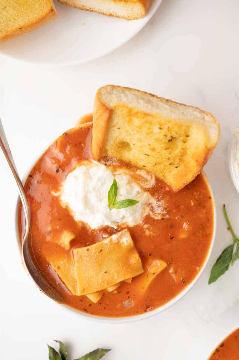Overhead view of lasagna soup with broken noodles in rich tomato broth topped with cheese. Hostess At Heart