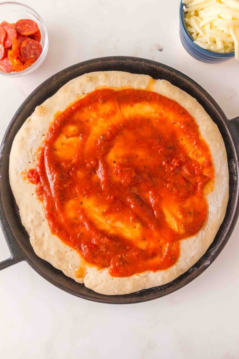 Pizza sauce slathered over partially baked homemade pizza dough no knead. Hostess At Heart