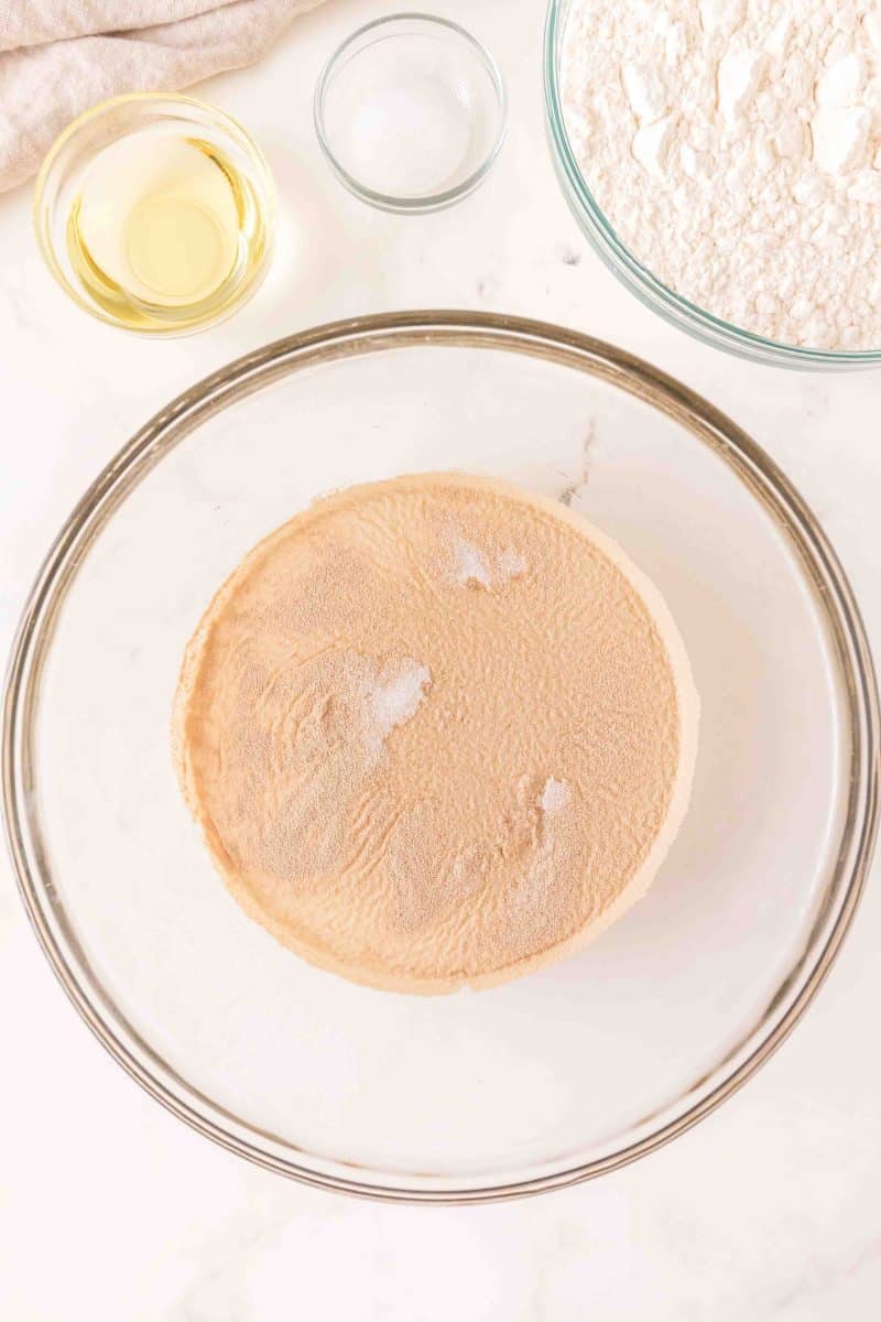 A mixing bowl containing warm water and sugar for activating yeast to make homemade dough. Hostess At Heart