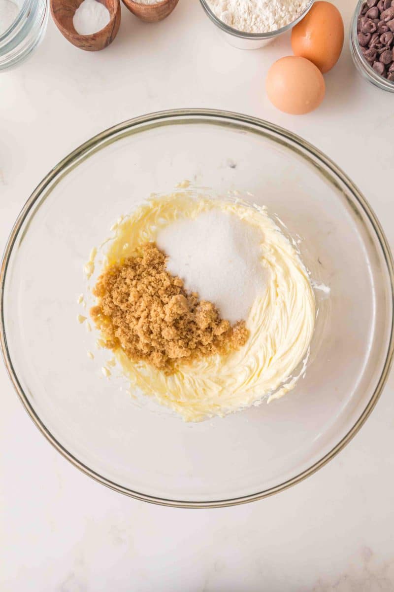 A mixing bowl containing whipped butter, brown sugar, and white sugar ready to be blended to make copycat crumble chocolate chip cookies. Hostess At Heart