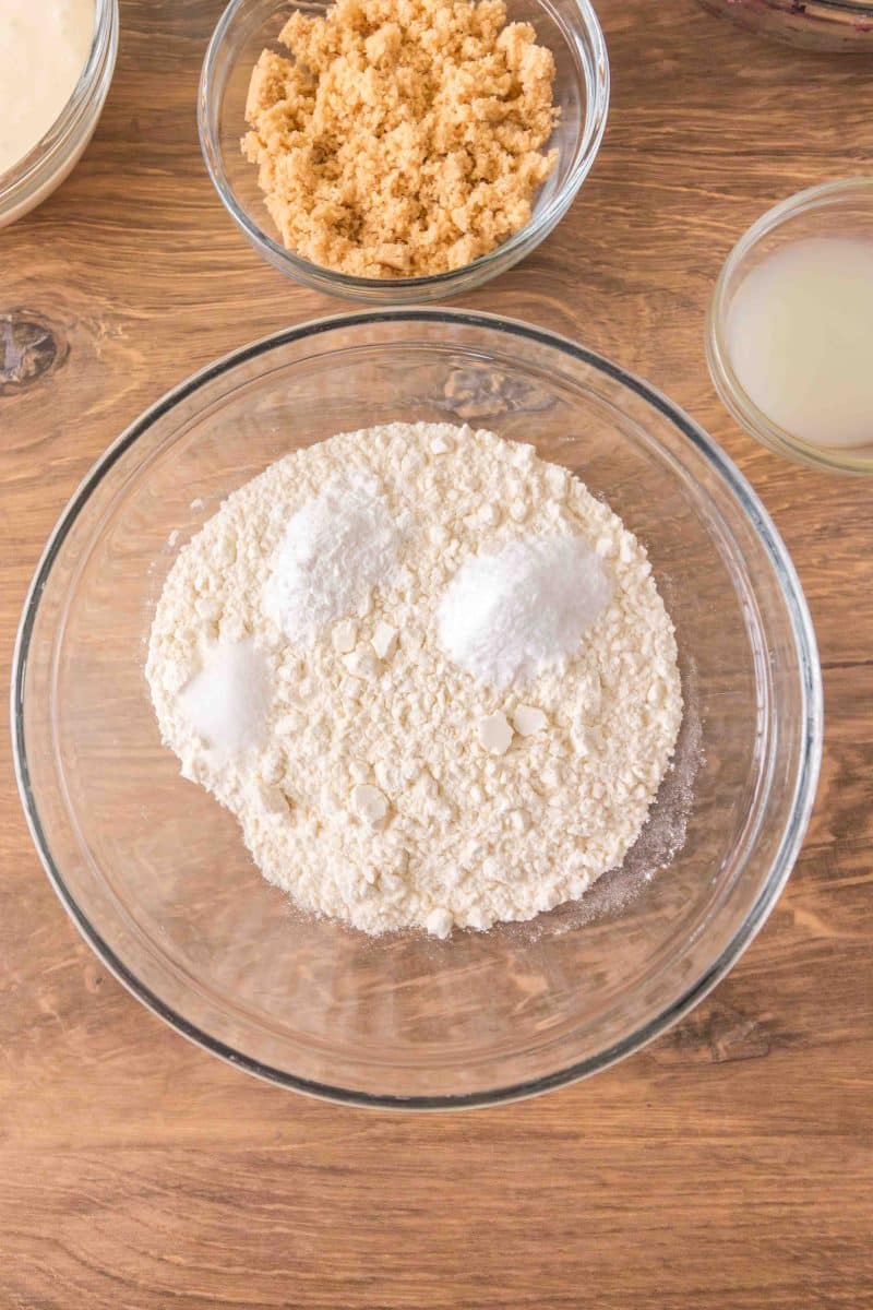 A mixing bowl containing the dry ingredients to make sourdough discard cobbler crust, flour, baking powder, baking soda, and salt. Hostess At Heart