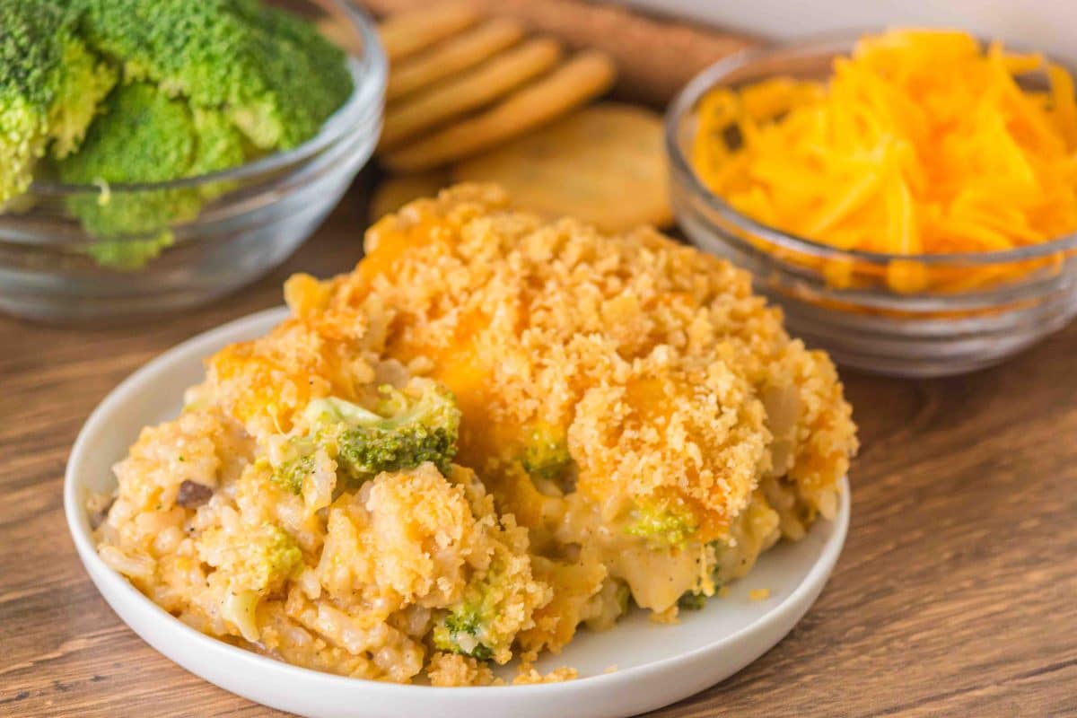 Close-up sideview of a serving of broccoli rice casserole with mushroom soup on a white plate. Hostess At Heart