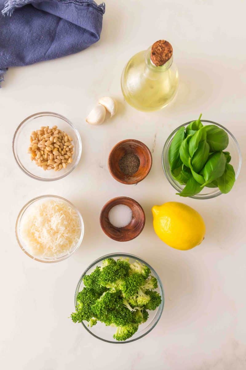 Ingredients to make an easy broccoli pesto recipe: blanched broccoli, salt, lemon, sweet basil, pine nuts, olive oil, garlic, and salt and pepper. Hostess At Heart