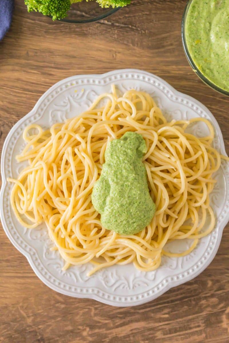 Overhead shot of broccoli pesto pasta sauce on top of spaghetti pasta ready to be tossed together. Hostess At Heart