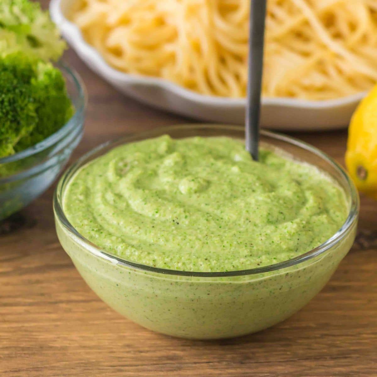 Sideview shot of finished broccoli pesto in a glass bowl. Hostess At Heart