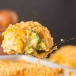 Close-up forkful of broccoli & rice casserole showing melted a melted creamy cheese in a sauce topped with crispy cracker topping. Hostess At Heart