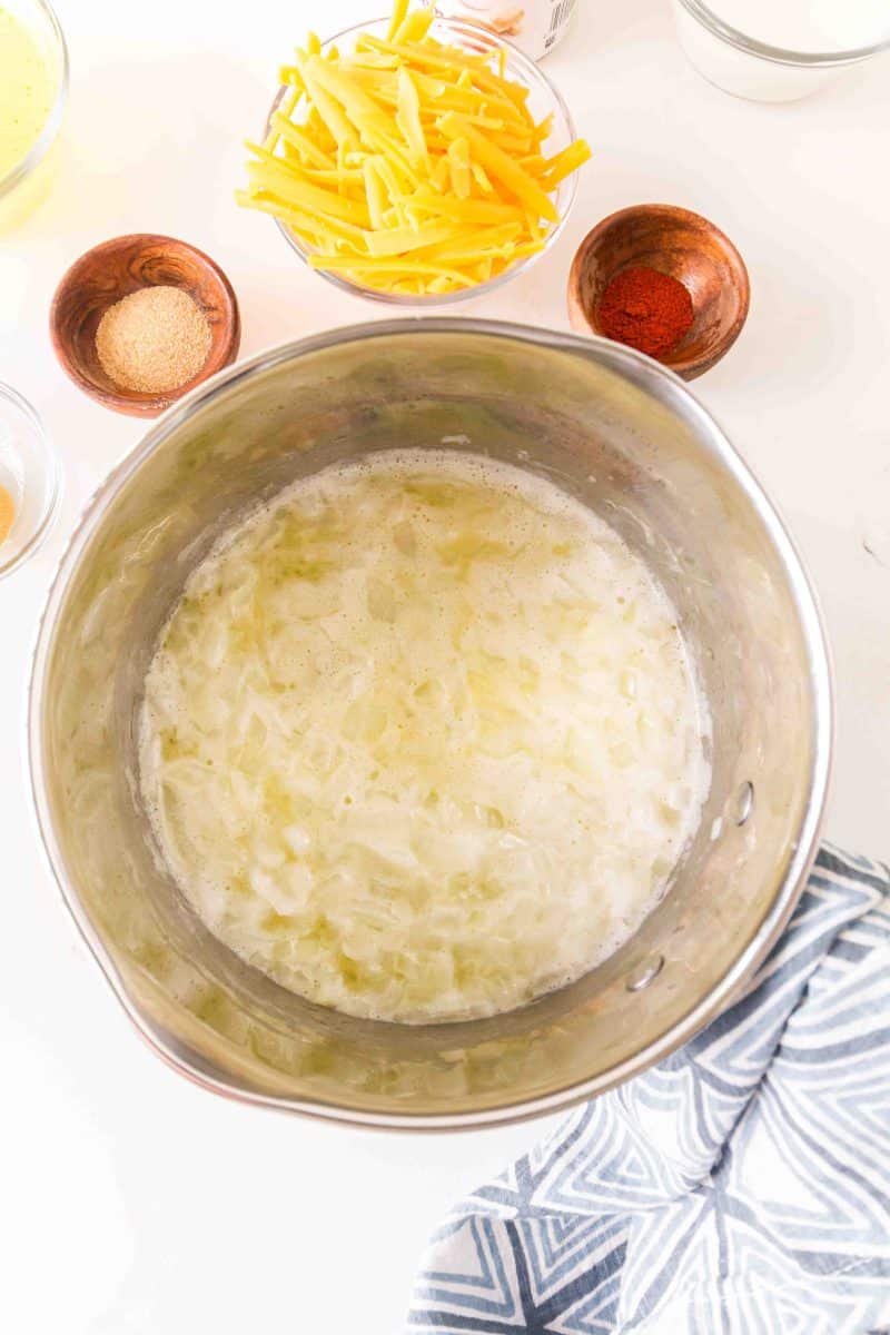 A saucepan filled with chicken stock, melted butter and softened butter to make a roux for a creamy broccoli rice cheddar casserole with mushroom soup. Hostess At Heart