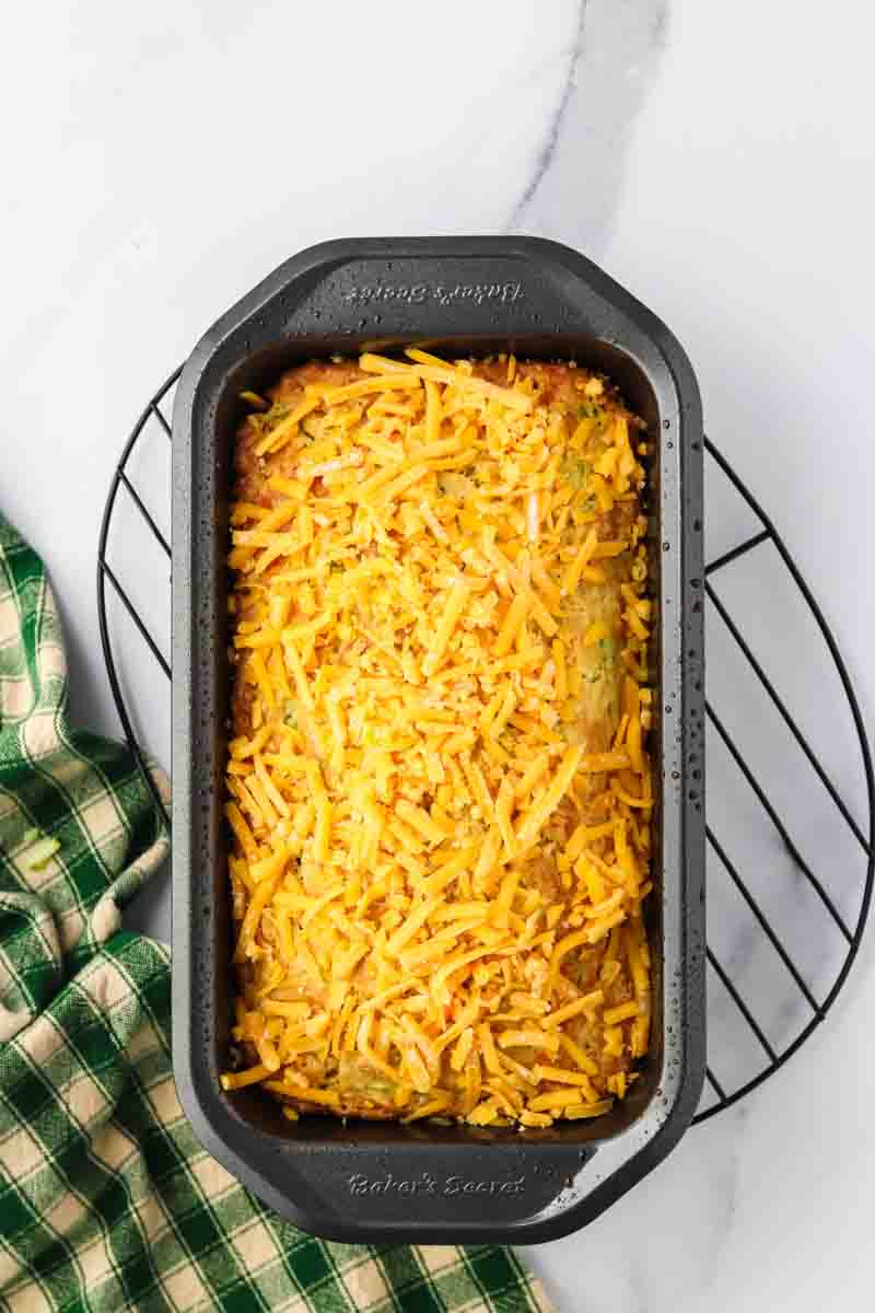 Fresh shredded cheddar cheese topping a loaf of zucchini cheese bread ready for the oven. Hostess At Heart