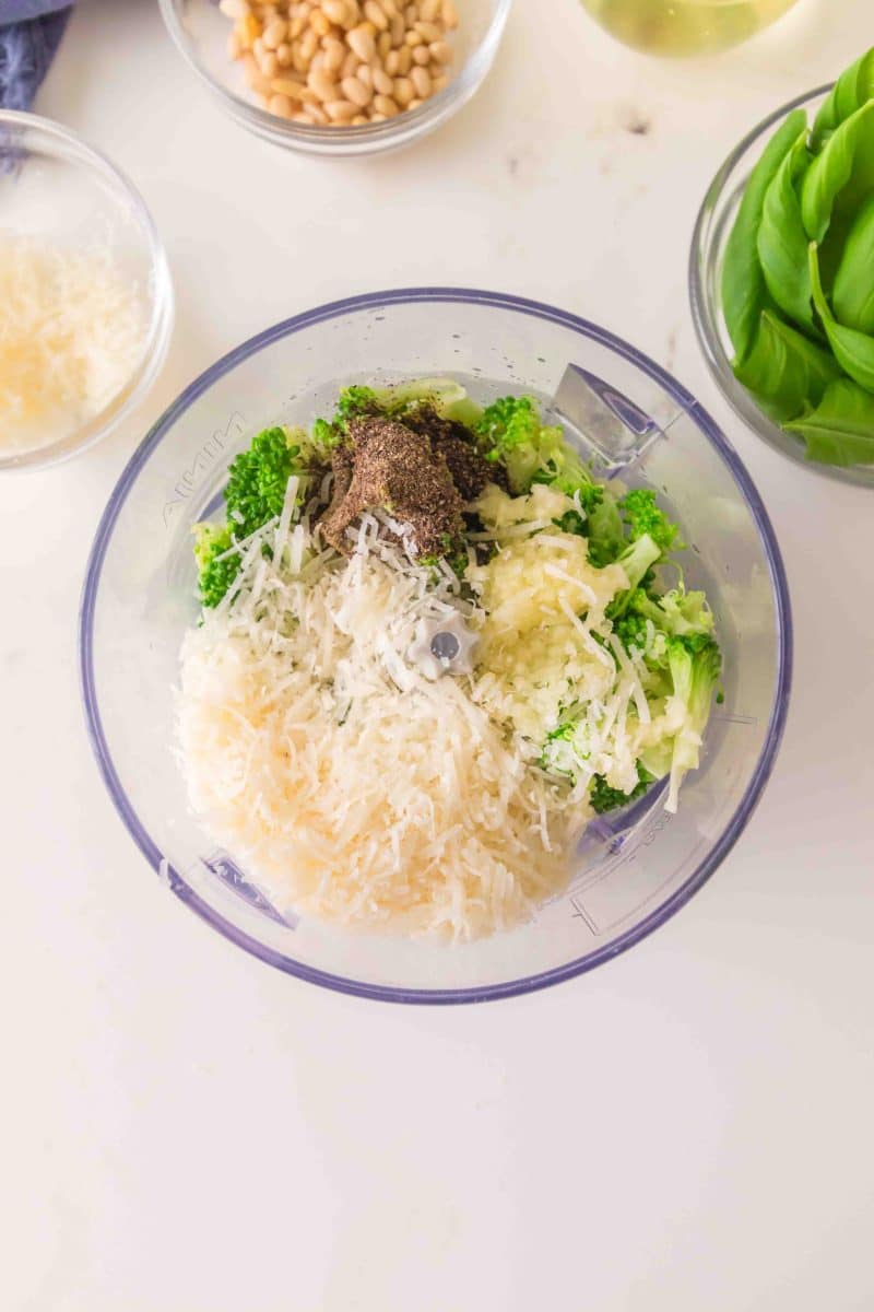 Garlic and Parmigiano Reggiano added to broccoli pesto ingredients in a food processor. Hostess At Heart