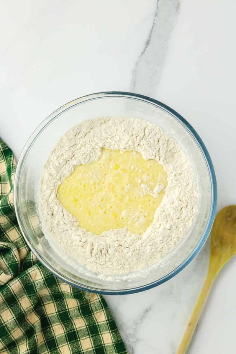 Zucchini Cheese Bread wet ingredients being added to the dry ingredients to make a quick bread batter. Hostess At Heart