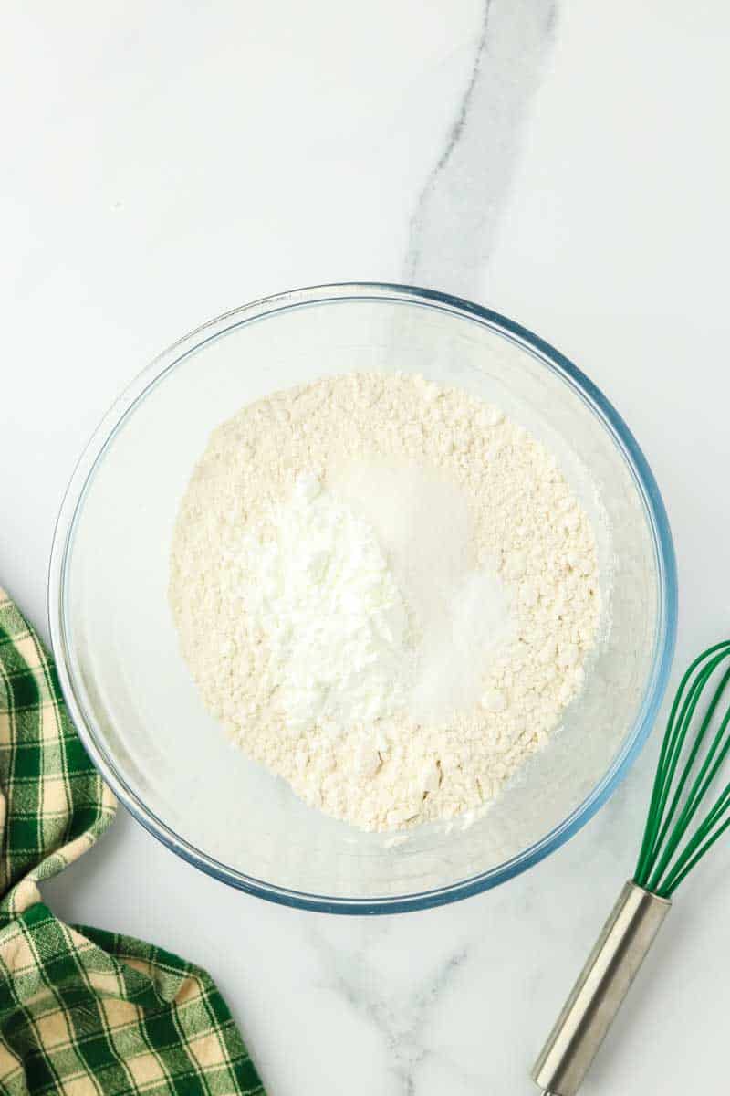 A mixing bowl filled with Zucchini and cheese bread dry ingredients: flour, baking soda, baking powder, sugar, and salt. Hostess At Heart