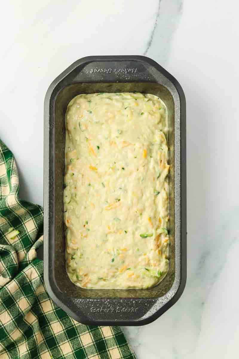 Zucchini cheese bread batter in a loaf pan before baking. Hostess At Heart