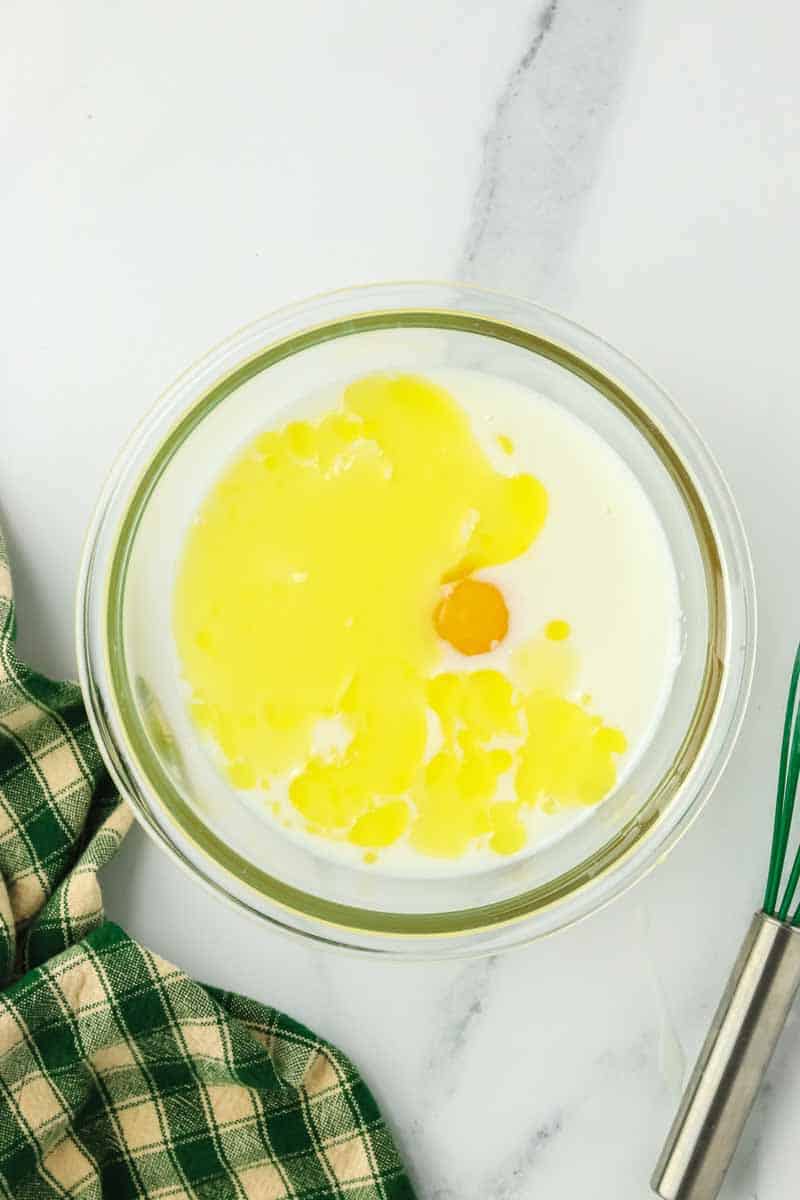 Buttermilk, egg, and melted butter in a mixing bowl to be whisked together to make Zucchini Cheese Quick Bread recipe. Hostess At Heart
