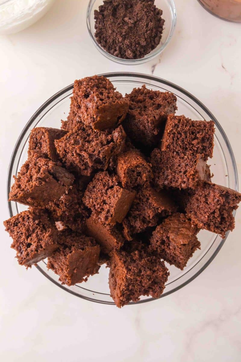 Chunks of chocolate cake in a mixing bowl ready to be layered into a chocolate pudding dessert. Hostess At Heart