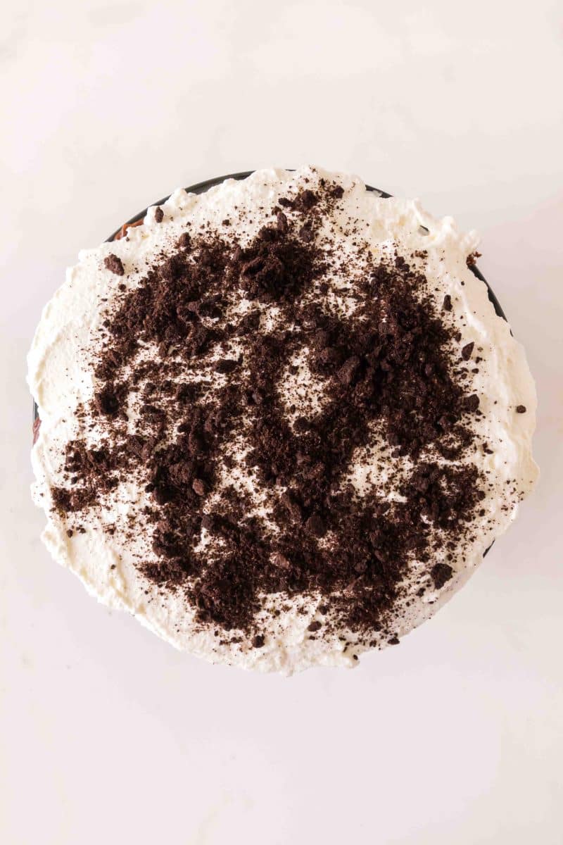 A overhead view of whipped topping sprinkled with crushed chocolate cookies to make a chocolate and cool whip dessert. Hostess At Heart