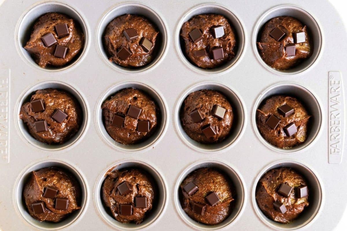 Muffin tin filled with chocolate pumpkin muffin batter before baking. Hostess At Heart