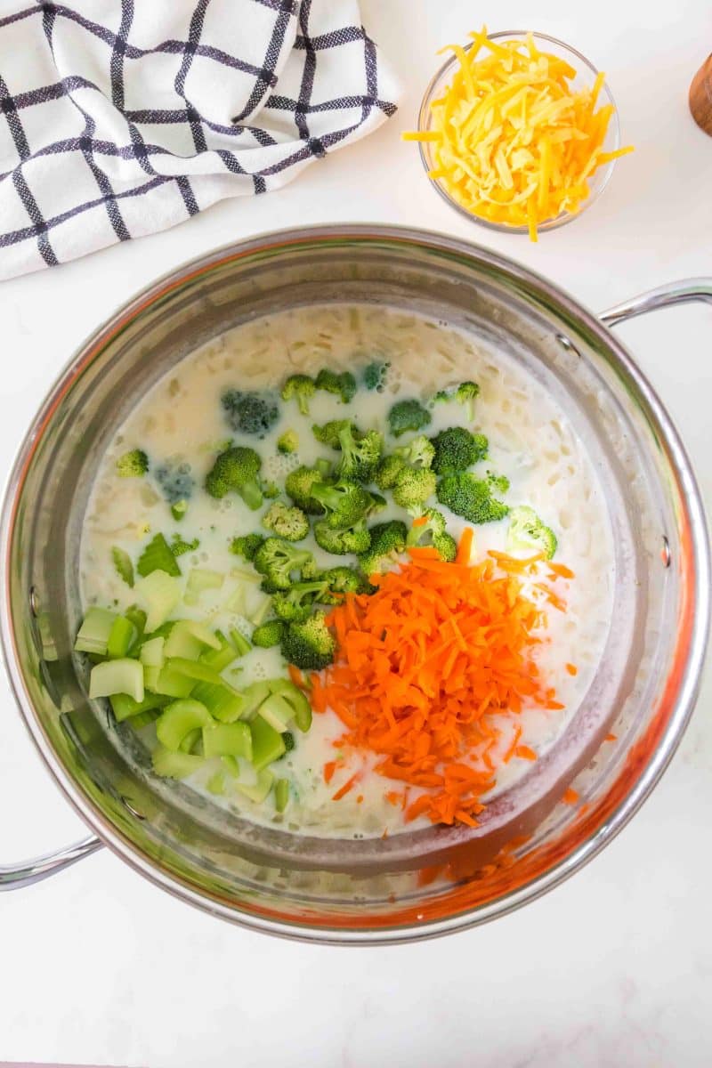 Broccoli, carrots, and celery simmering in creamy broth for broccoli cheddar soup. Hostess At Heart