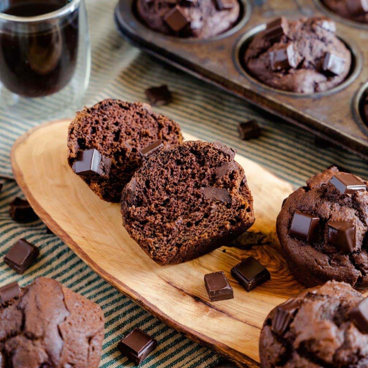 Chocolate pumpkin muffin cut in half showing a fudgy, moist center with chunks of chocolate. Hostess At Heart