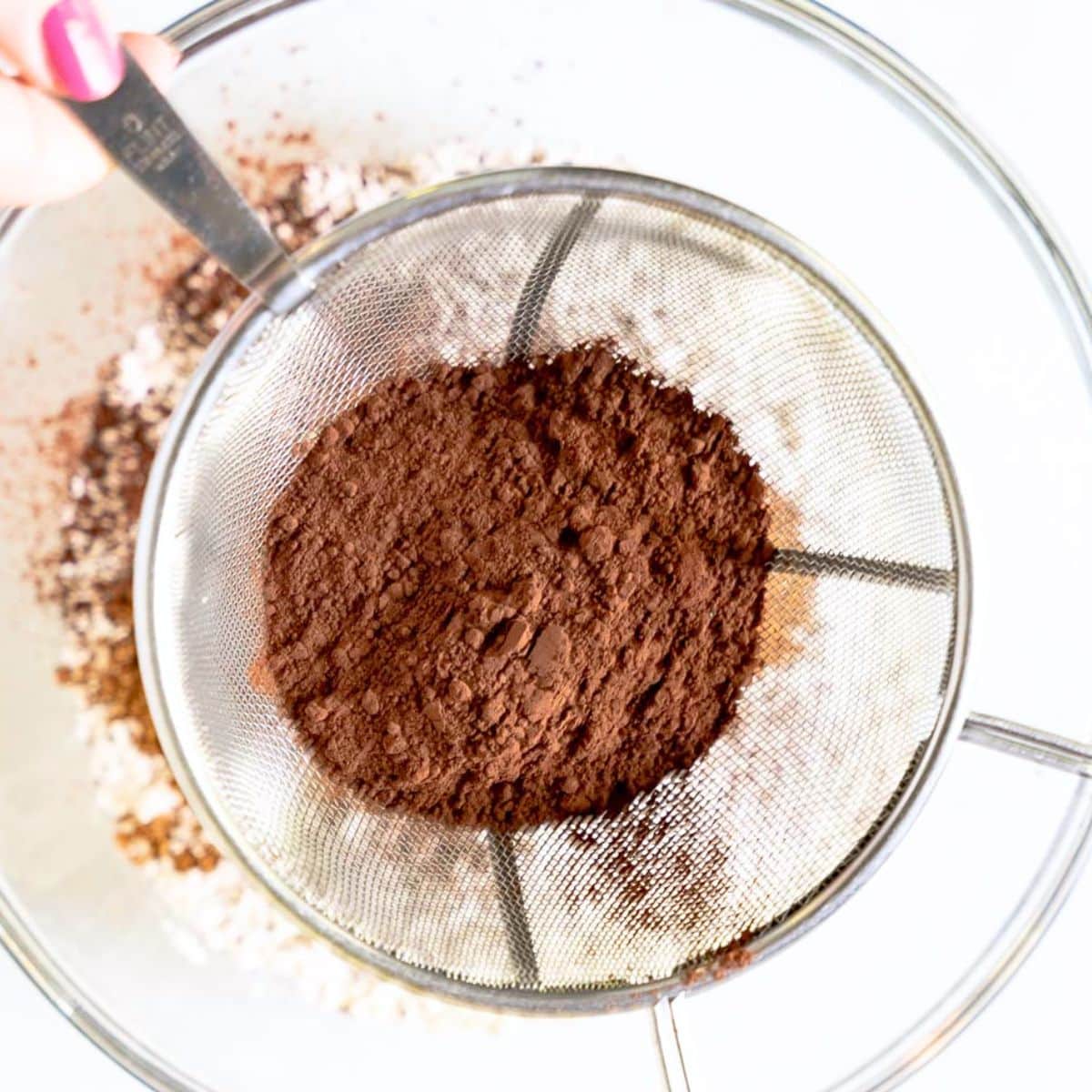Sifting cocoa powder into a bowl for chocolate pumpkin muffin batter. Hostess At Heart
