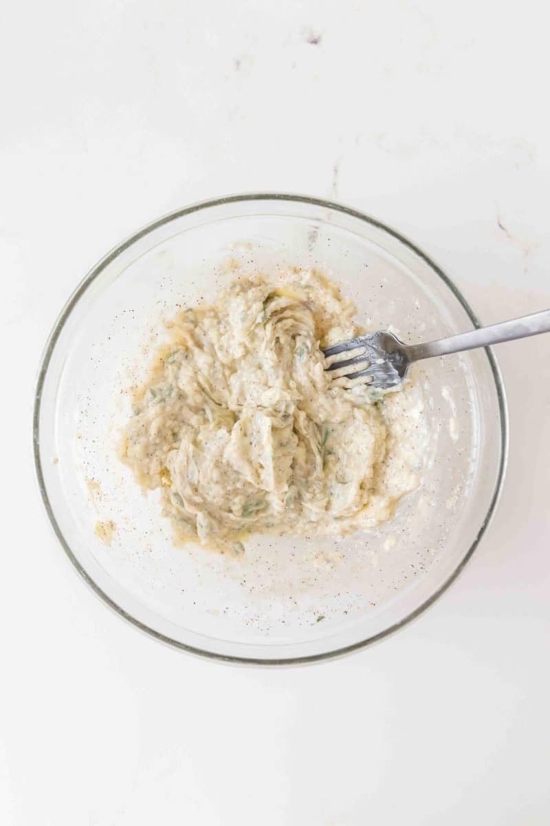 Herb butter mixed with garlic, rosemary, and thyme in glass bowl. Hostess At Heart